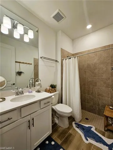 a bathroom with a sink a toilet a mirror and shower