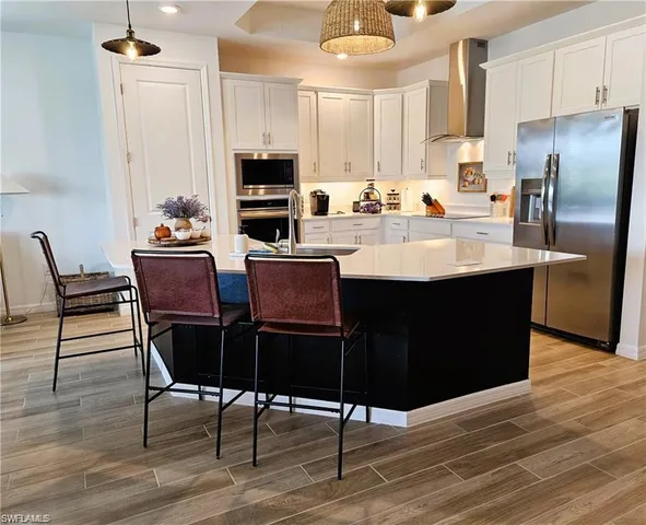 a kitchen with stainless steel appliances kitchen island granite countertop a table chairs and a refrigerator