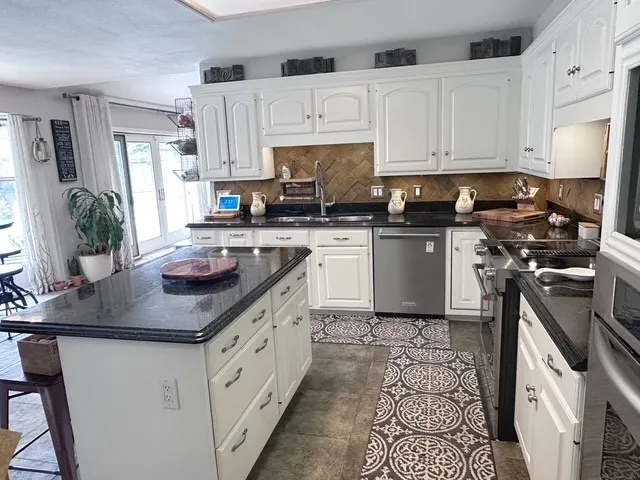 a kitchen with stainless steel appliances a stove a sink a microwave a refrigerator and chairs