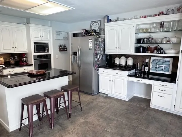 a kitchen with stainless steel appliances kitchen island granite countertop a table chairs sink and cabinets