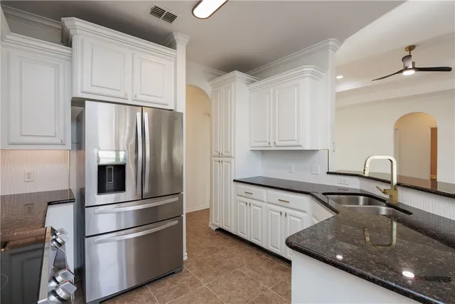 a kitchen with stainless steel appliances granite countertop a refrigerator a sink and white cabinets