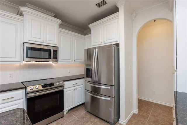 a metallic refrigerator freezer and a stove sitting inside of a kitchen