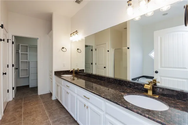 a spacious bathroom with a granite countertop double vanity sink a mirror and a shower