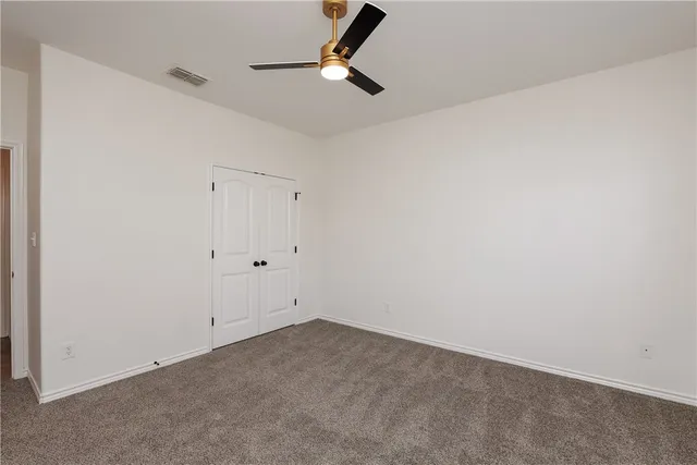 an empty room with ceiling fan and window