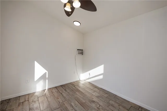 a view of an empty room with wooden floor and window