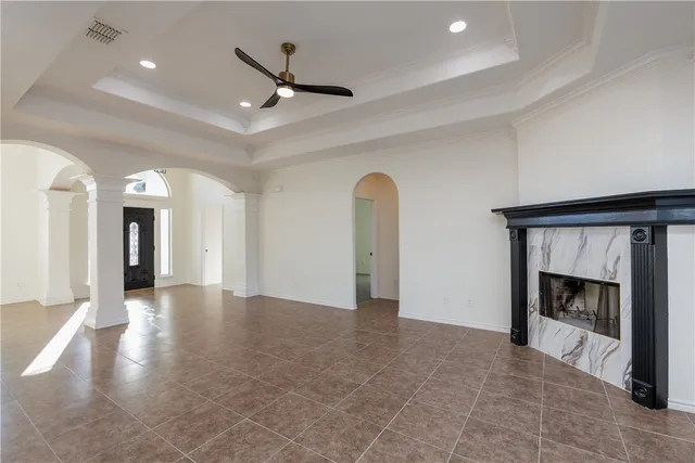 a view of an empty room with kitchen and a fireplace
