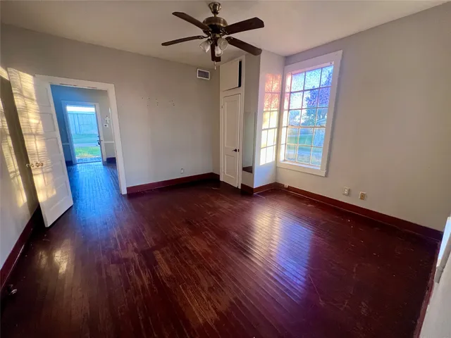 a view of empty room with wooden floor and fan