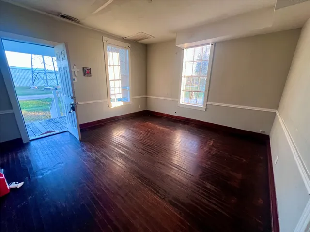 an empty room with wooden floor and windows