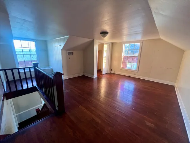 a view of a hallway with wooden floor and windows
