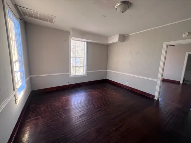 an empty room with wooden floor and windows