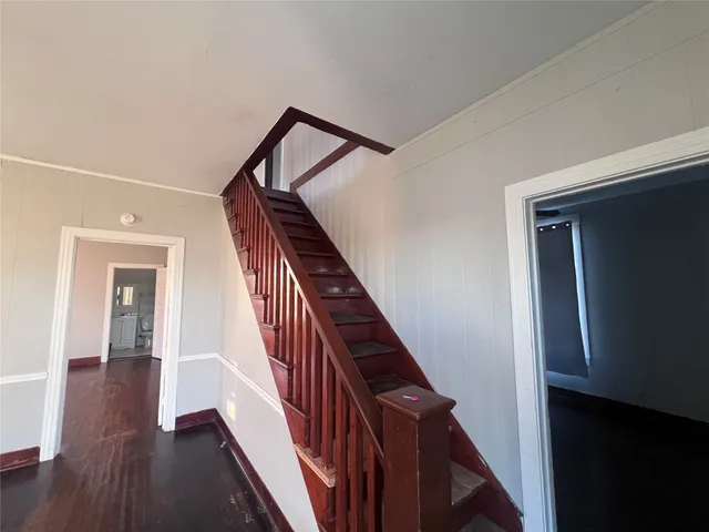 a view of a hallway with wooden floor and stairs