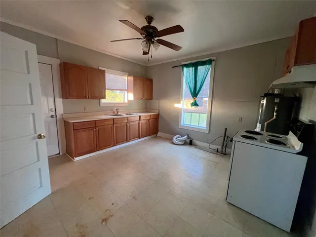 a kitchen with granite countertop a stove sink and cabinets