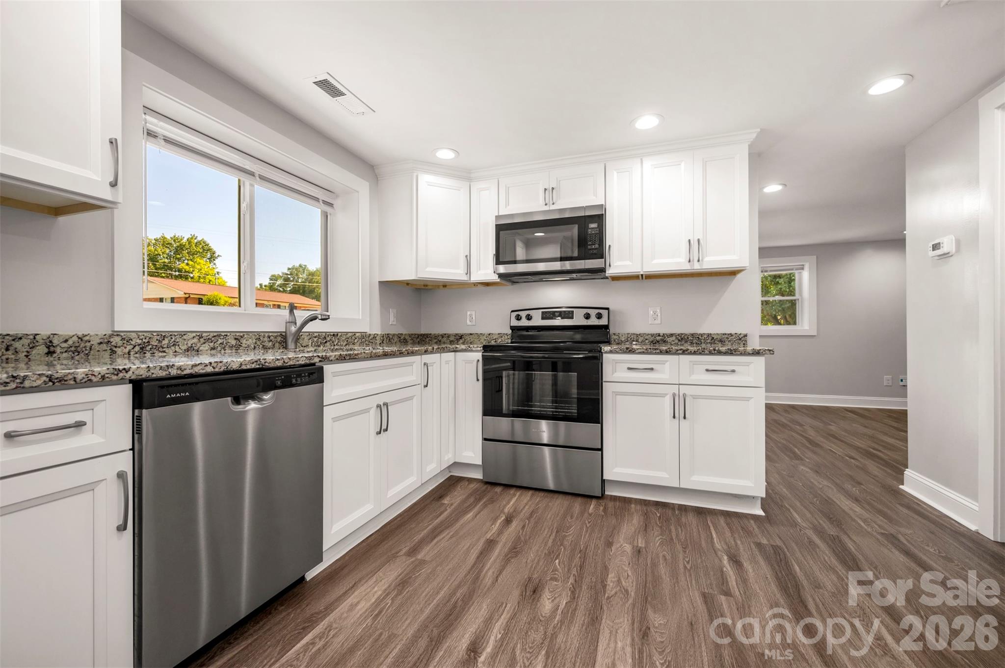 220 Roberson Road Forest City, NC 28043 - Photo 7 of 35 a kitchen with stainless steel appliances granite countertop wooden cabinets a sink a stove a microwave and wooden floors
