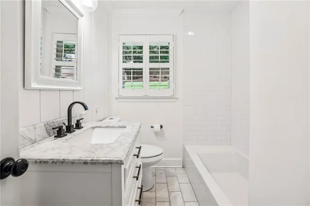 a bathroom with a granite countertop sink a toilet and a bathtub