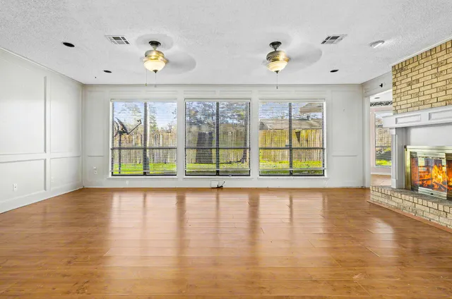 a view of an empty room with wooden floor fireplace and a window