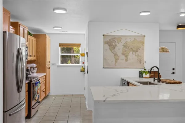 a living room with stainless steel appliances furniture a refrigerator and a window