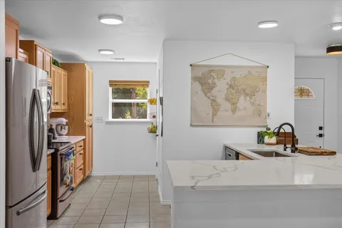 a living room with stainless steel appliances furniture a refrigerator and a window