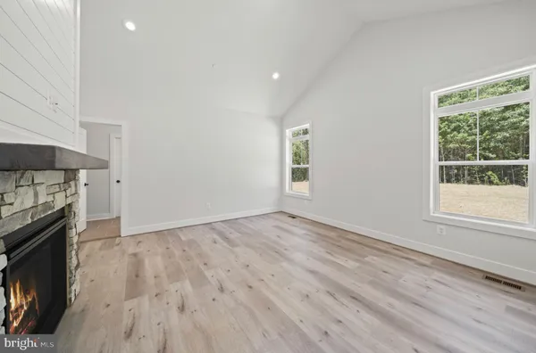 a living room with stainless steel appliances wooden floor and a fireplace