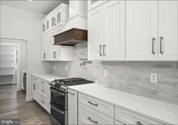 a large white kitchen with wooden floor and a window