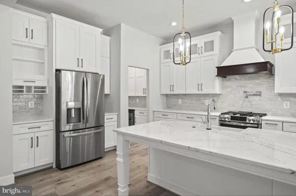 a large kitchen with granite countertop a lot of white cabinets and stainless steel appliances