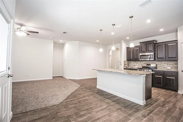 a kitchen with stainless steel appliances granite countertop a sink a stove and a refrigerator