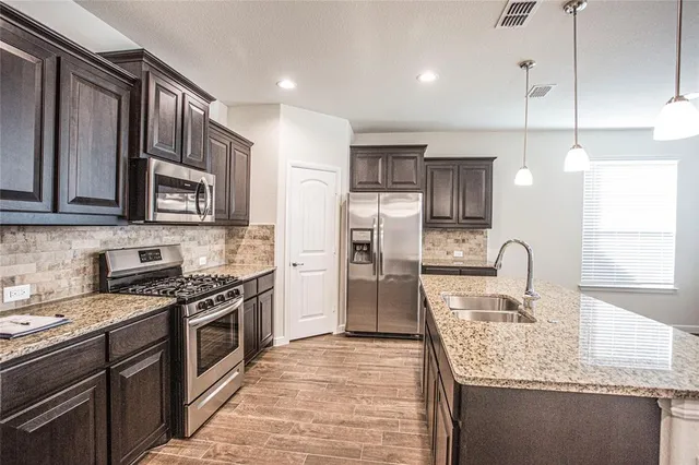 a kitchen with stainless steel appliances granite countertop a sink stove and refrigerator