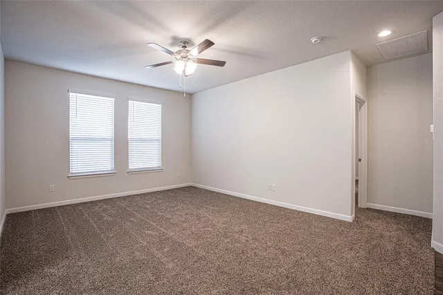 an empty room with windows and fan