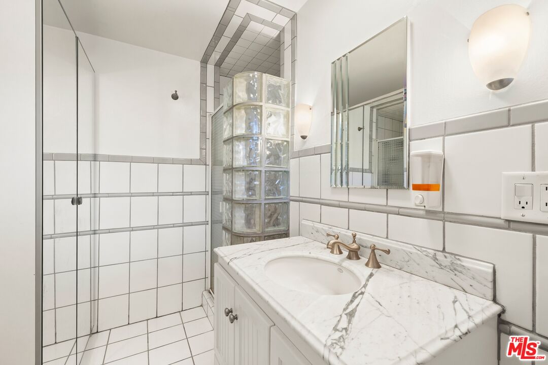 1444 Roscomare Road Los Angeles, CA 90077 - Photo 10 of 19 a bathroom with a granite countertop sink and a mirror