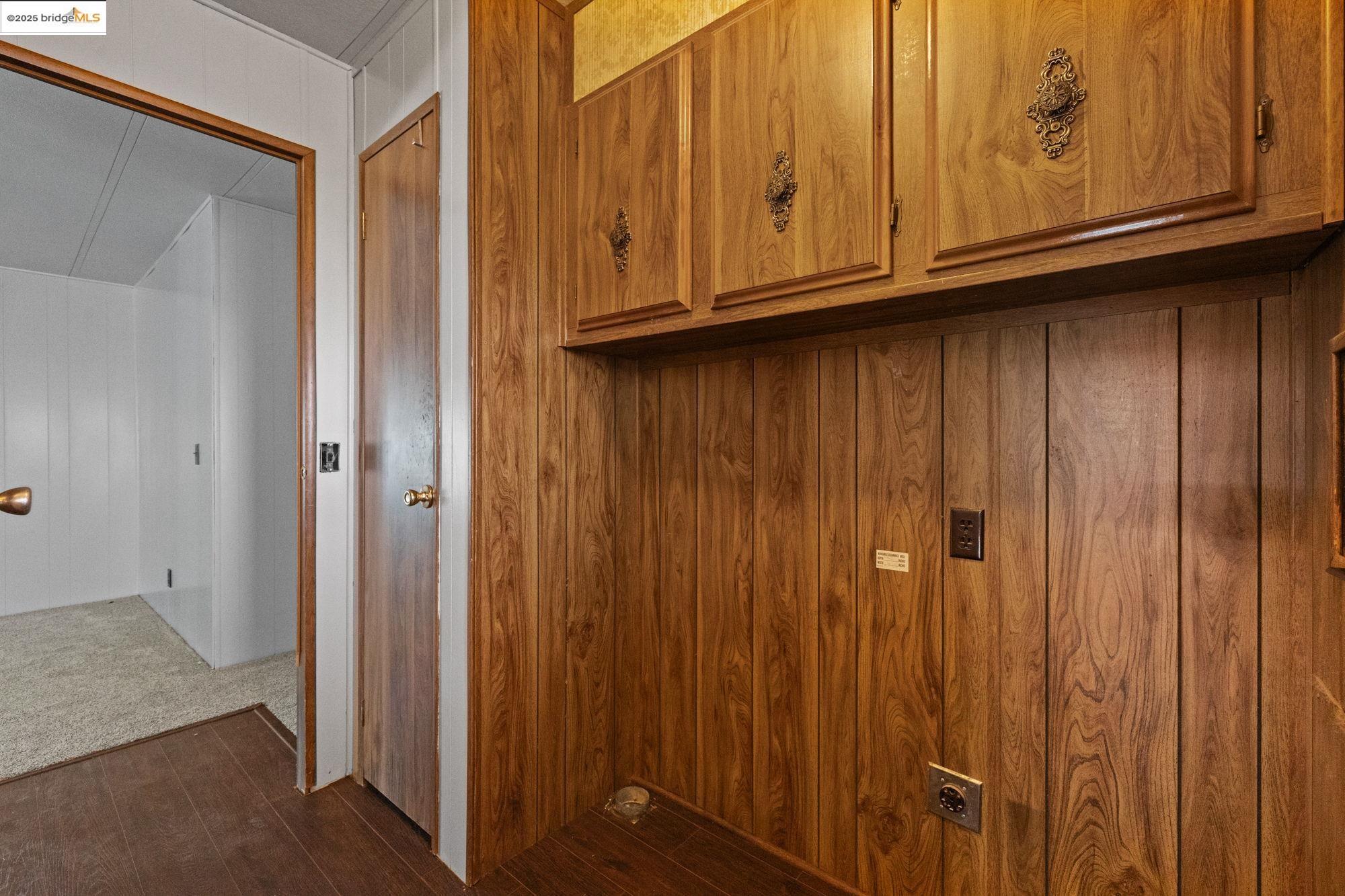 10956 Green Street, Unit 186 Columbia, CA 95310 - Photo 13 of 21 Laundry area with wood walls and dark wood finished floors