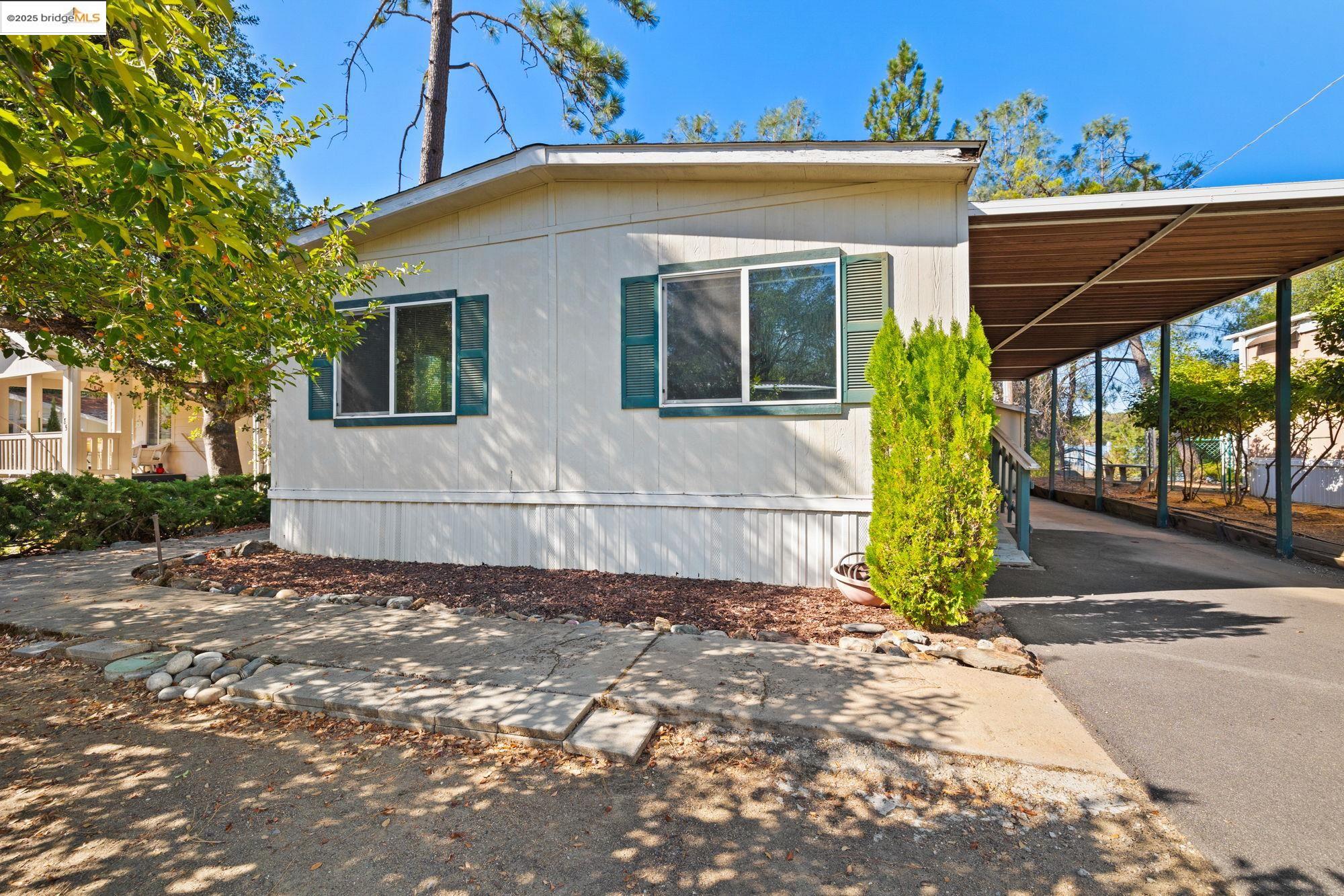 10956 Green Street, Unit 186 Columbia, CA 95310 - Photo 2 of 21 View of side of home featuring asphalt driveway and a carport