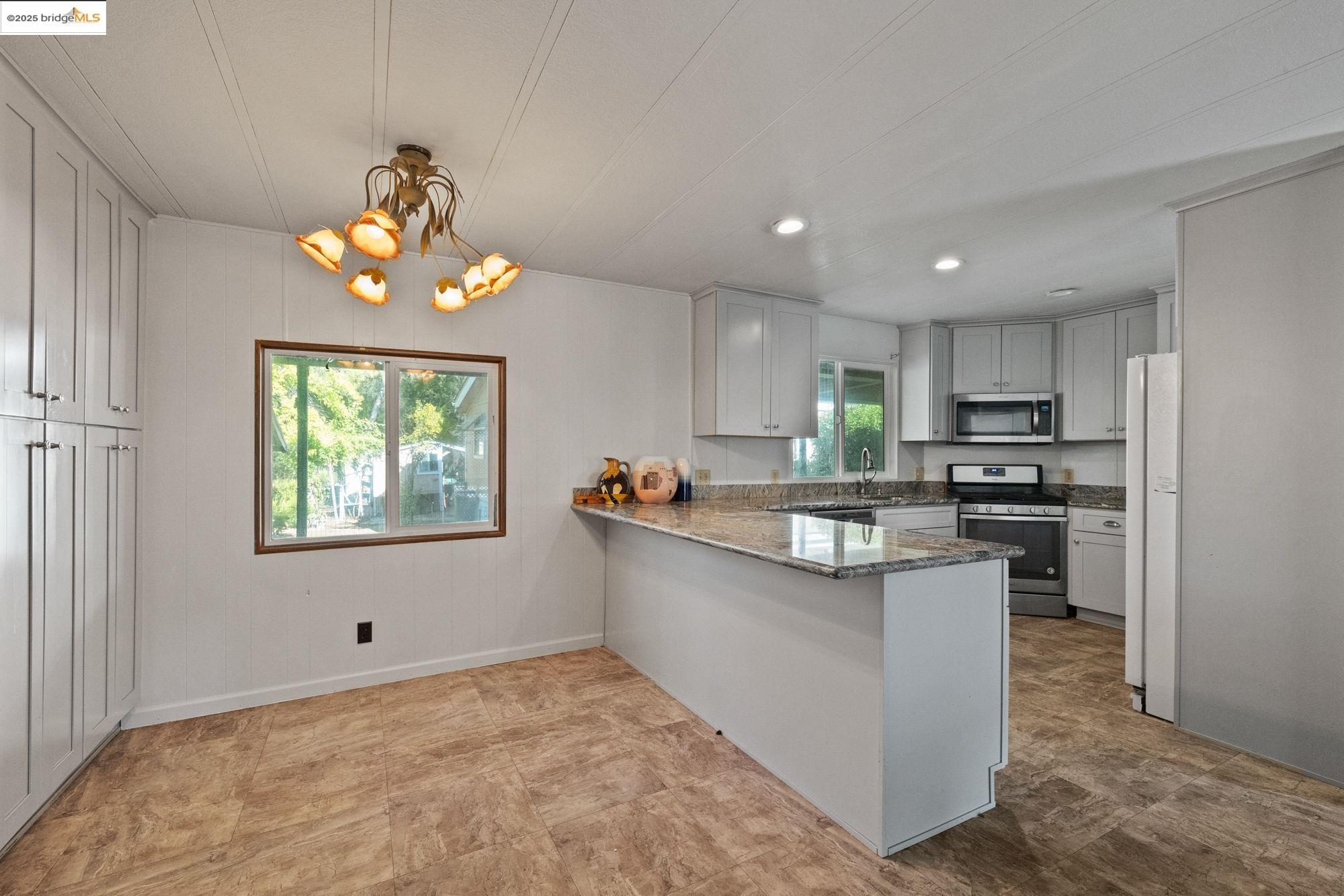 10956 Green Street, Unit 186 Columbia, CA 95310 - Photo 6 of 21 Kitchen with dark stone countertops, appliances with stainless steel finishes, a peninsula, a chandelier, and recessed lighting
