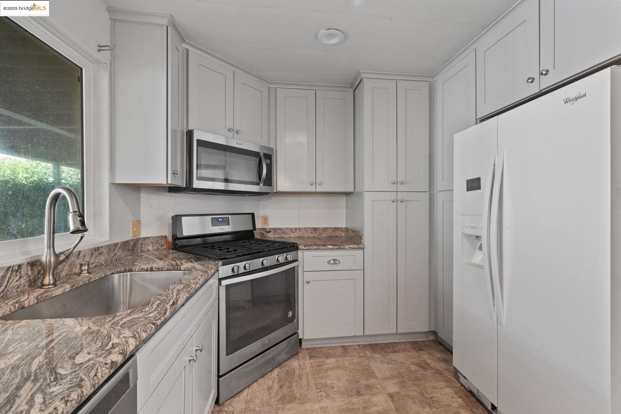 10956 Green Street, Unit 186 Columbia, CA 95310 - Photo 8 of 21 Kitchen with stainless steel appliances, light stone countertops, and white cabinetry