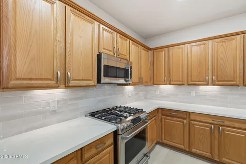 an empty room with a chandelier fan and wooden floor
