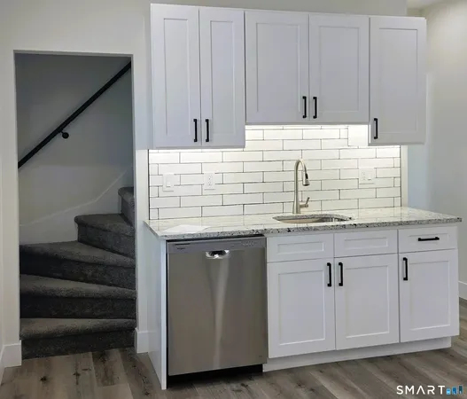 a view of kitchen with granite countertop white cabinets and stainless steel appliances