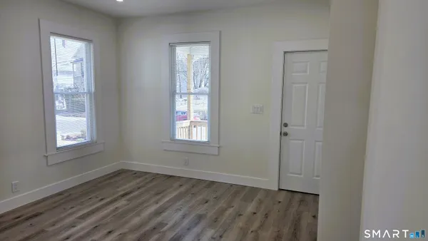 a view of an empty room with wooden floor and a window