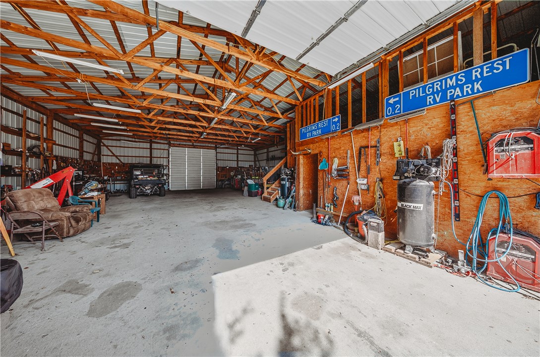 21587 West Hickory Flat Road Springdale, AR 72764 - Photo 36 of 45 Spacious shop interior with a concrete floor, overhead door, lighting, work areas, and additional loft storage.