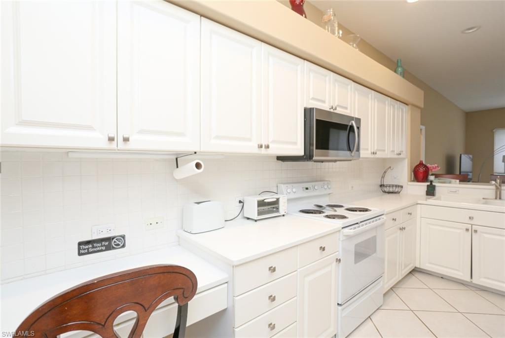 164 Spring Lake Circle Naples, FL 34119 - Photo 14 of 36 a kitchen with cabinets appliances a sink and a counter top space