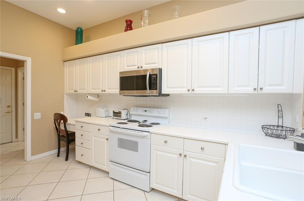 164 Spring Lake Circle Naples, FL 34119 - Photo 15 of 36 a kitchen with white cabinets stainless steel appliances and sink