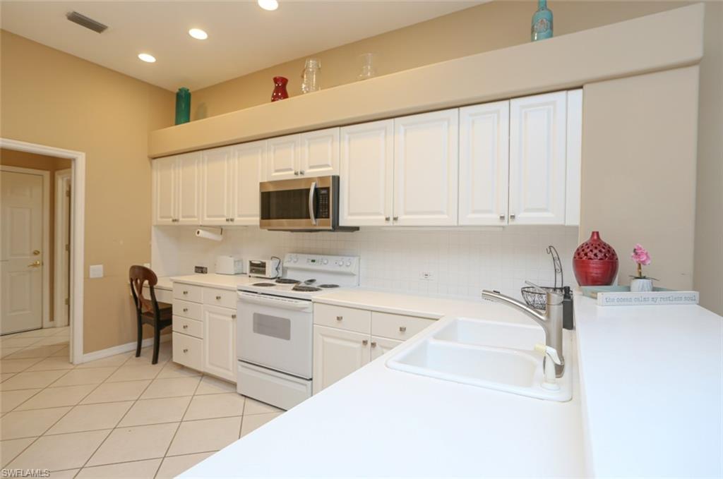 164 Spring Lake Circle Naples, FL 34119 - Photo 16 of 36 a kitchen with granite countertop white cabinets and stainless steel appliances