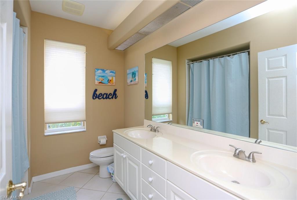 164 Spring Lake Circle Naples, FL 34119 - Photo 19 of 36 a bathroom with a granite countertop sink toilet and a mirror