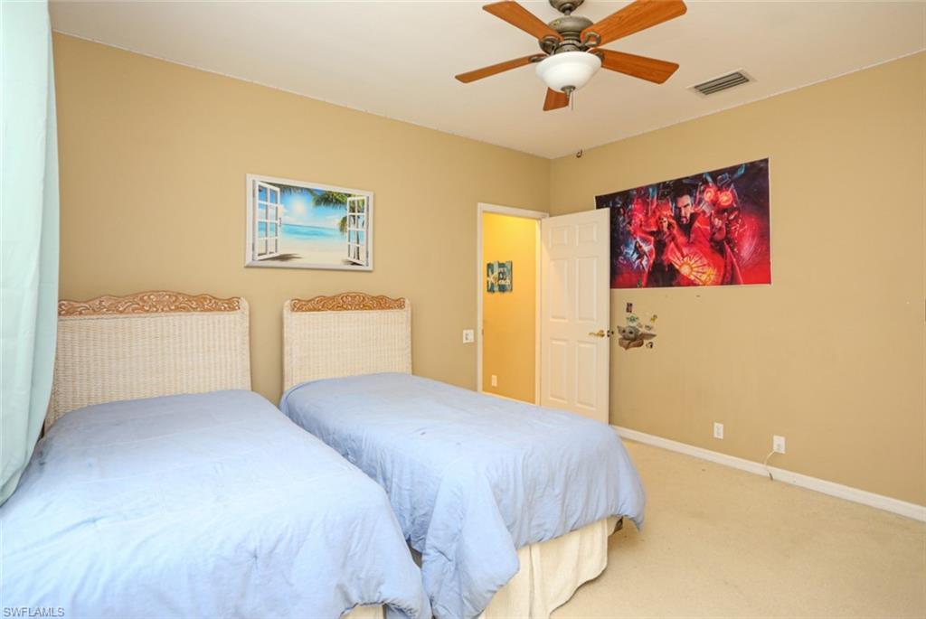 164 Spring Lake Circle Naples, FL 34119 - Photo 22 of 36 a bedroom with a large bed and a chandelier