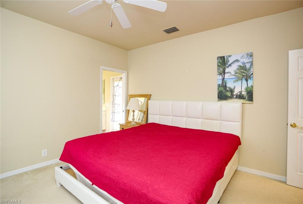 164 Spring Lake Circle Naples, FL 34119 - Photo 23 of 36 a bedroom with a bed and a potted plant