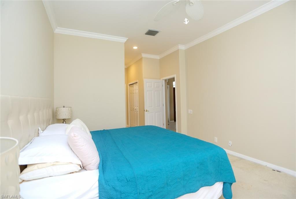 164 Spring Lake Circle Naples, FL 34119 - Photo 31 of 36 a bedroom with a bed and a mirror