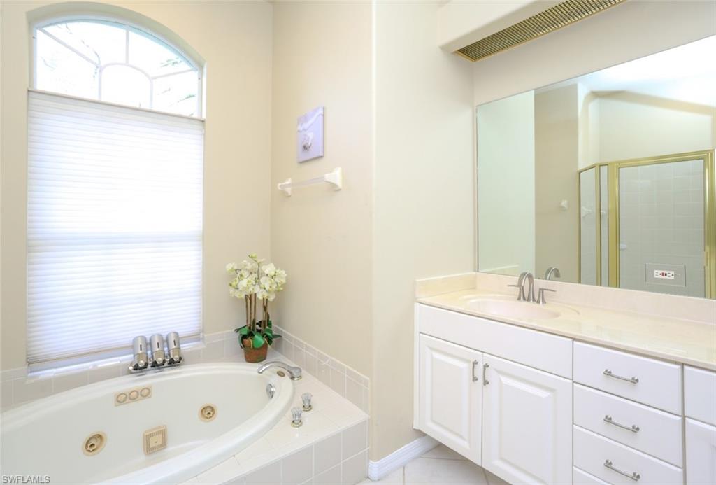 164 Spring Lake Circle Naples, FL 34119 - Photo 33 of 36 a bathroom with a bathtub sink and mirror