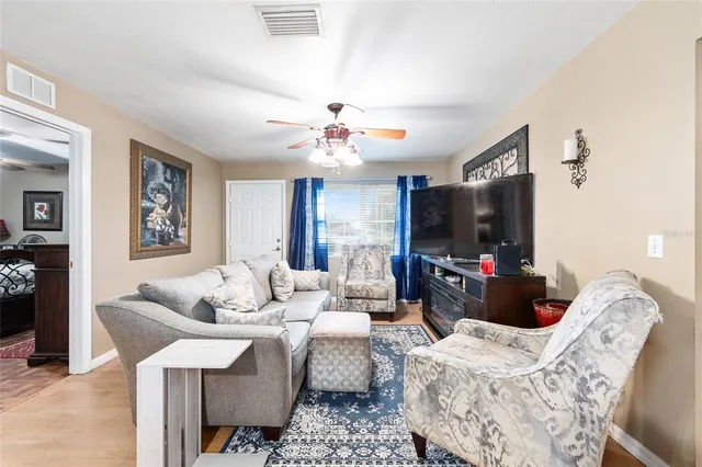 a living room with furniture a flat screen tv and a chandelier