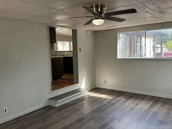 a view of an empty room with wooden floor and a window