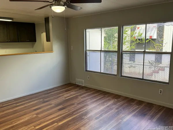 a view of an empty room with wooden floor and a window
