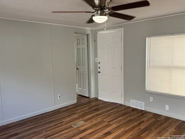 a view of empty room with wooden floor and fan