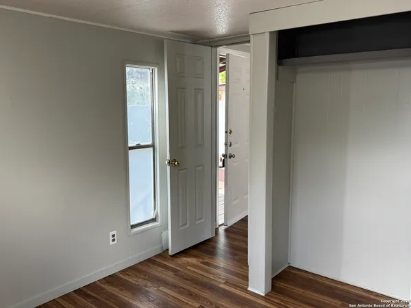 a view of an empty room with wooden floor and closet