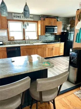 a kitchen with stainless steel appliances kitchen island granite countertop a table chairs in it and wooden floors